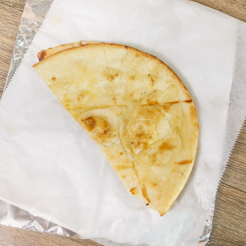 Two golden-brown folded flatbreads served on white paper over a wooden table.